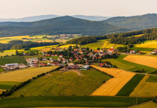 Aerial view of a small rural village surrounded by fields and hills, taken from a tiny house location.