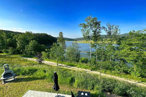 Zicht vanuit Holiday village SEEBLICK - Tiny Chalet am Eixendorfer See op het meer, bomen en heldere lucht.