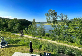 Blick vom Holiday village SEEBLICK - Tiny Chalet am Eixendorfer See auf einen ruhigen See und grüne Landschaft.