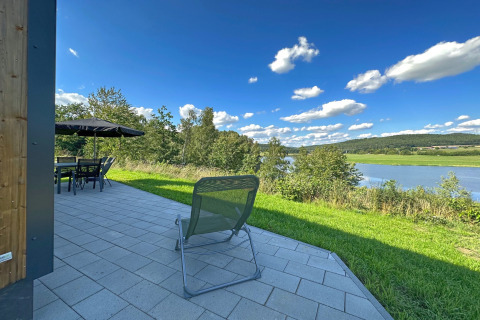 Patio con sedia e tavolo all'aperto, vista sul lago Eixendorfer See e colline verdi in Germania.