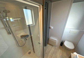 Bagno moderno in tiny house SEEBLICK sul lago Eixendorfer, con doccia, finestra e wc sospeso a muro.