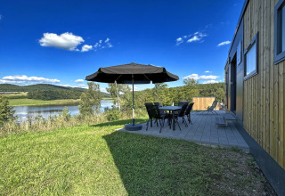 Udsigt over søen fra terrassen ved Holiday village SEEBLICK - Tiny Chalet am Eixendorfer See med borde og parasol.