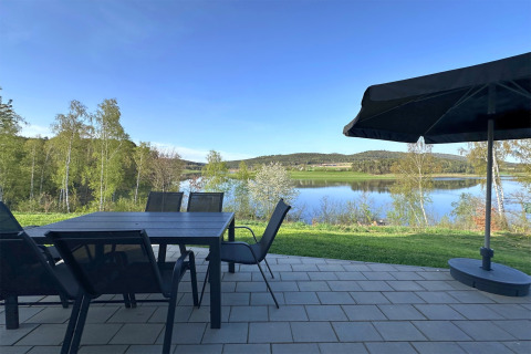 Terrasse avec table, chaises et parasol, vue sur un lac et des collines près d'un tiny house en Allemagne.