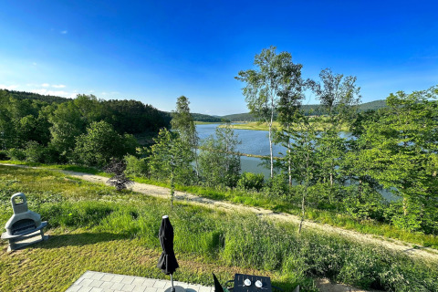 Vista sul lago e colline verdi da Holiday village «SEEBLICK - Tiny Chalet am Eixendorfer See» in Germania.