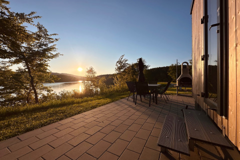 Solnedgang set fra terrasse ved Holiday village «SEEBLICK - Tiny Chalet am Eixendorfer See» med udsigt til sø.