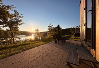 Solnedgang set fra terrasse ved Holiday village «SEEBLICK - Tiny Chalet am Eixendorfer See» med udsigt til sø.