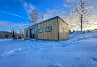 Tiny house moderno en Holiday village SEEBLICK junto al Eixendorfer See, Alemania, rodeado de nieve y cielo azul.