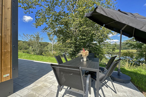 Patio esterno al SEEBLICK Tiny Chalet am Eixendorfer See in Germania, con tavolo, sedie e ombrellone.