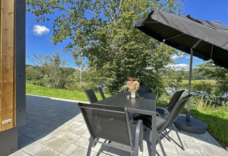Udendørs terrasse ved SEEBLICK Tiny Chalet am Eixendorfer See i Tyskland, med bord, stole og parasol.