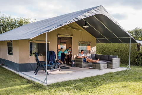 Safari tent Resort Begur 3 with family relaxing on the terrace, comfy outdoor furniture, and grassy scenery.