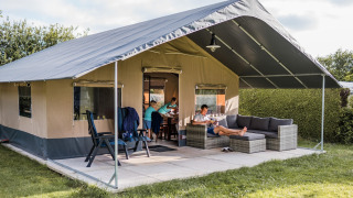 Safaritent Resort Begur 3 met familie ontspannen op het terras, comfortabele zetels en groene omgeving.