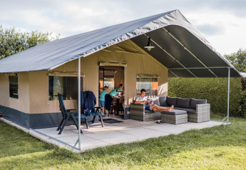 Tente safari Resort Begur 3, famille détendue sur la terrasse, mobilier confortable et cadre verdoyant.