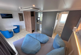 Intérieur d'une tiny house moderne au Holiday village SEEBLICK, avec lit, cuisine et espace salon.