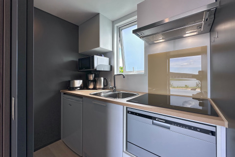 Modern compact kitchen at Holiday village SEEBLICK Tiny Chalet am Eixendorfer See, with a window view outside.