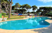 Buitenzwembad met glijbanen en ligstoelen bij CAMPING INTERPALS- Bungalow Sa Riera in Spanje, tussen bomen.