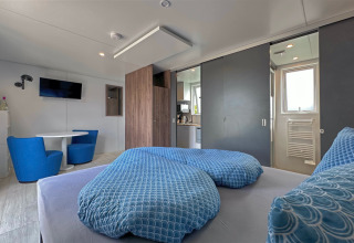 Acogedora tiny house moderna con ropa de cama azul y cocina junto al lago Eixendorfer See, Alemania.