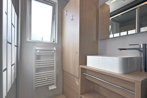 Moderne badeværelse i et tiny house på Holiday village SEEBLICK, med vask, vindue og træskabe, Tyskland.