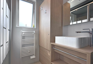 Bagno moderno in una tiny house al villaggio Holiday SEEBLICK, con finestra, lavabo e mobili in legno, Germania.