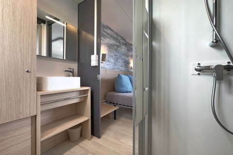 Modern bathroom with shower and sink, view into bedroom of a tiny house at Eixendorfer See, Germany.