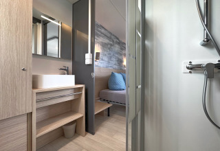 Modernes Badezimmer mit Dusche und Waschbecken, Blick ins Schlafzimmer eines Tiny Chalets in Deutschland.