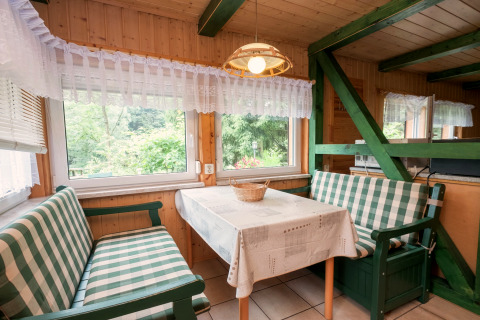 Essbereich in der Lodge Neustadt, Deutschland, mit karierten Bänken, Holzwänden und großen Fenstern.