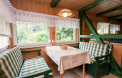 Dining area in Neustadt lodge, Germany, with checkered benches, wood walls, and large scenic windows.