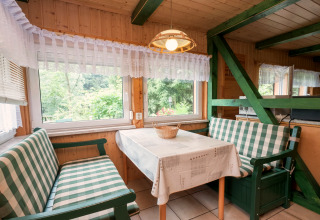 Essbereich in der Lodge Neustadt, Deutschland, mit karierten Bänken, Holzwänden und großen Fenstern.