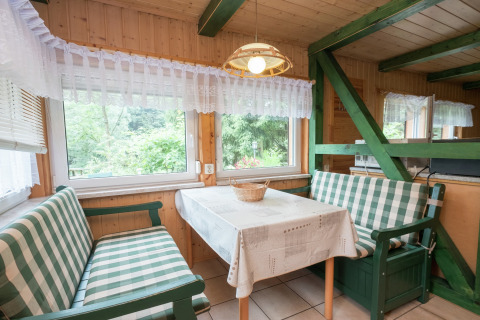 Eethoek in lodge Neustadt, Duitsland, met geruite banken, houten wanden en grote ramen met uitzicht.
