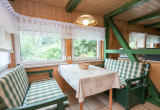 Eethoek in lodge Neustadt, Duitsland, met geruite banken, houten wanden en grote ramen met uitzicht.