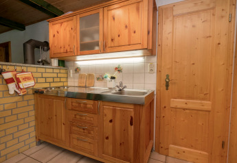 Kitchen area with wooden cabinets, stainless steel countertop, and tiled wall at Neustadt lodge in Germany.