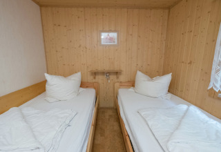 Twee eenpersoonsbedden met wit beddengoed in een knusse houten kamer van de Neustadt-lodge in Duitsland.