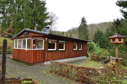 Houten lodge genaamd Neustadt in Duitsland, omgeven door groene bomen, buitenaanzicht overdag.