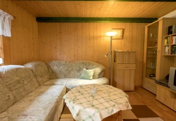 Cozy living room at Neustadt lodge in Germany featuring a corner sofa, floor lamp, and wood walls.
