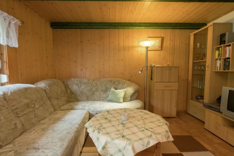 Gezellige woonkamer in lodge Neustadt, Duitsland, met hoekbank, staande lamp en houten wanden.