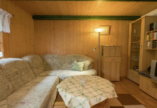 Gezellige woonkamer in lodge Neustadt, Duitsland, met hoekbank, staande lamp en houten wanden.