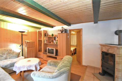 Gezellige woonkamer in lodge Neustadt in Duitsland met houten lambrisering, kachel en zachte zitjes.