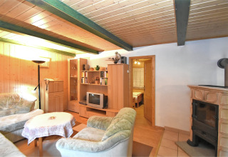 Gezellige woonkamer in lodge Neustadt in Duitsland met houten lambrisering, kachel en zachte zitjes.