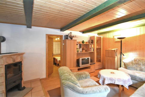 Gezellige woonkamer in lodge Neustadt in Duitsland met houten plafond, open haard en comfortabele bank.