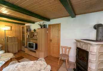 Cozy living room at Neustadt lodge in Germany with wood stove, wooden furniture and TV set.