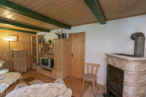Gezellige woonkamer in de Neustadt-lodge in Duitsland met houtkachel, houten meubilair en tv.