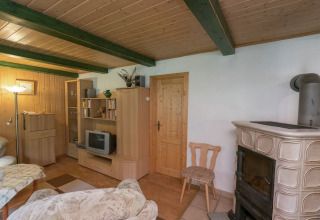 Gezellige woonkamer in de Neustadt-lodge in Duitsland met houtkachel, houten meubilair en tv.