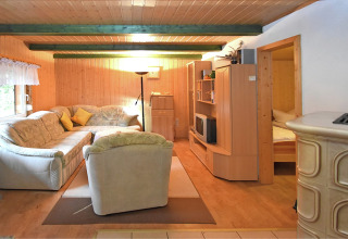 Woonkamer in lodge Neustadt in Duitsland met houten wanden, comfortabele bank en rustieke inrichting.