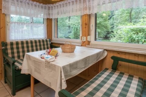 Gezellige eethoek in lodge Neustadt in Duitsland, met geruite banken, tafelkleed en bosuitzicht.
