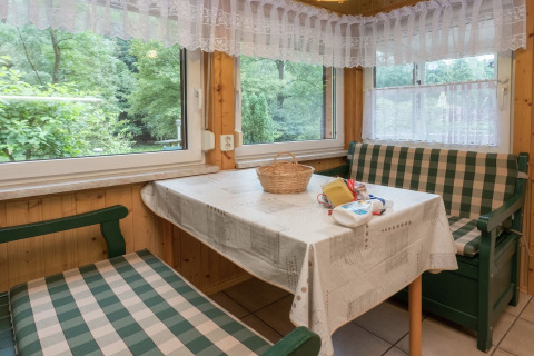Knusse eethoek in lodge Neustadt, Duitsland met geruite banken, witte tafelkleed en uitzicht op het bos.
