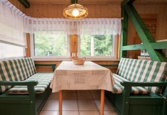 Cozy dining area at Lodge Neustadt, Germany, with green checkered benches and large windows.