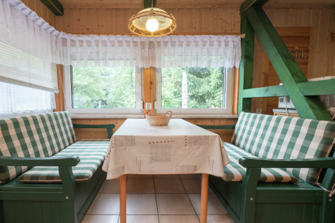 Knusse eethoek in lodge Neustadt in Duitsland met groene geruite banken en grote ramen.