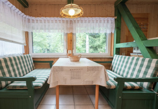 Knusse eethoek in lodge Neustadt in Duitsland met groene geruite banken en grote ramen.