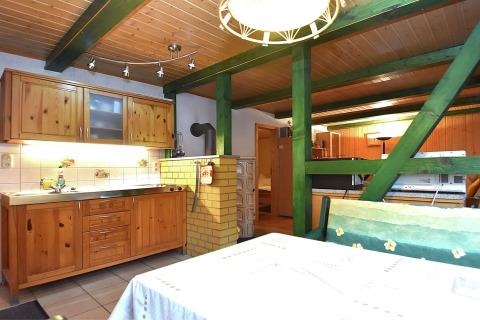 Knusse keuken en eetruimte met houten kasten, groene balken en gele stenen in de Neustadt-lodge, Duitsland.