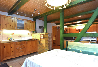 Knusse keuken en eetruimte met houten kasten, groene balken en gele stenen in de Neustadt-lodge, Duitsland.