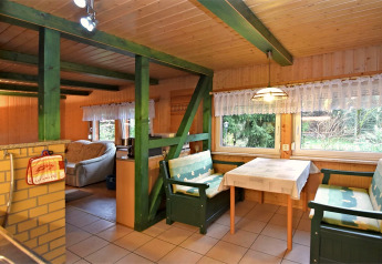 Cozy interior of the 'Neustadt' lodge in Germany featuring green beams, dining table, and benches.
